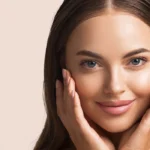 Close-up of a young woman with clear, glowing skin gently touching her face, showcasing smooth eyelids and natural beauty, ideal for promoting interest in no-incision eyelid surgery